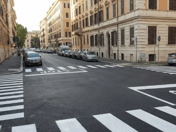 Vista di un incrocio urbano con segnaletica orizzontale bianca appena rifatta, incluse strisce pedonali, linea di arresto e scritta STOP, conformi al Codice della Strada.